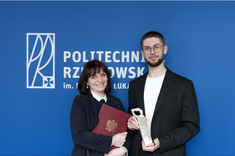 Od lewej: dr inż. arch. Joanna Dudek oraz mgr inż. arch. Przemysław Dybaś pozują do zdjęcia na tle niebieskiej ściany