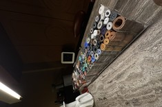 Showroom Metaforma Design prezentuje ekspozycję różnokolorowych rulonów materiałów wykończeniowych, ułożonych w kilku rzędach