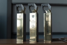 Trzy statuetki od lewej: dla Pani dr inż. Joanny Krasoń, dla Pani mgr inż. arch. Pauliny Wiącek oraz dla Pana mgr. inż. arch. Przemysława Dybasia stoją obok siebie stoją na stole