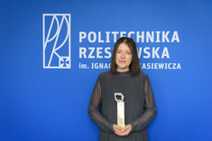 Dr inż. Joanna Krasoń pozuje do zdjęcia na tle niebieskiej ściany