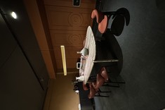 Strefa jadalniana w showroomie Metaforma Design: owalny stół z czerwonymi krzesłami na tle dekoracyjnej ściany z geometryczną sztukaterią.